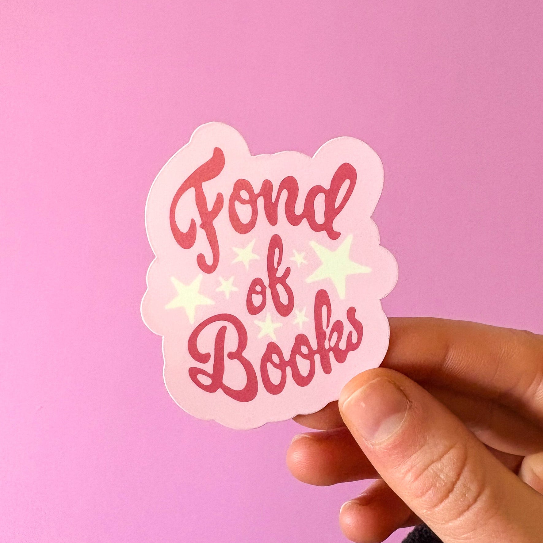 Sticker with 'Fond of Books' text held against a pink background