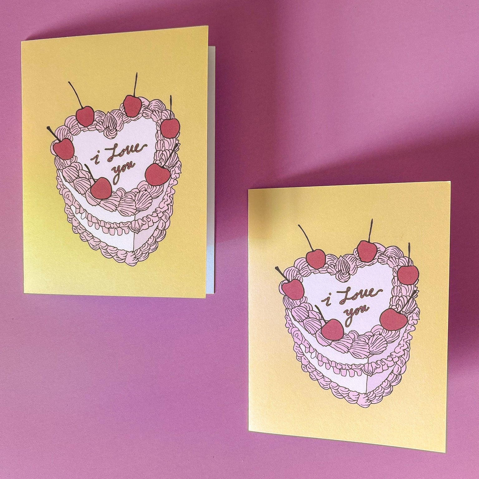 Two yellow greeting cards with heart designs and 'I love you' text on a pink background