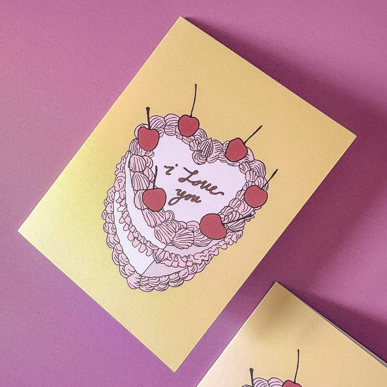 Two yellow cards with cake illustrations and 'I Love You' text on a pink background
