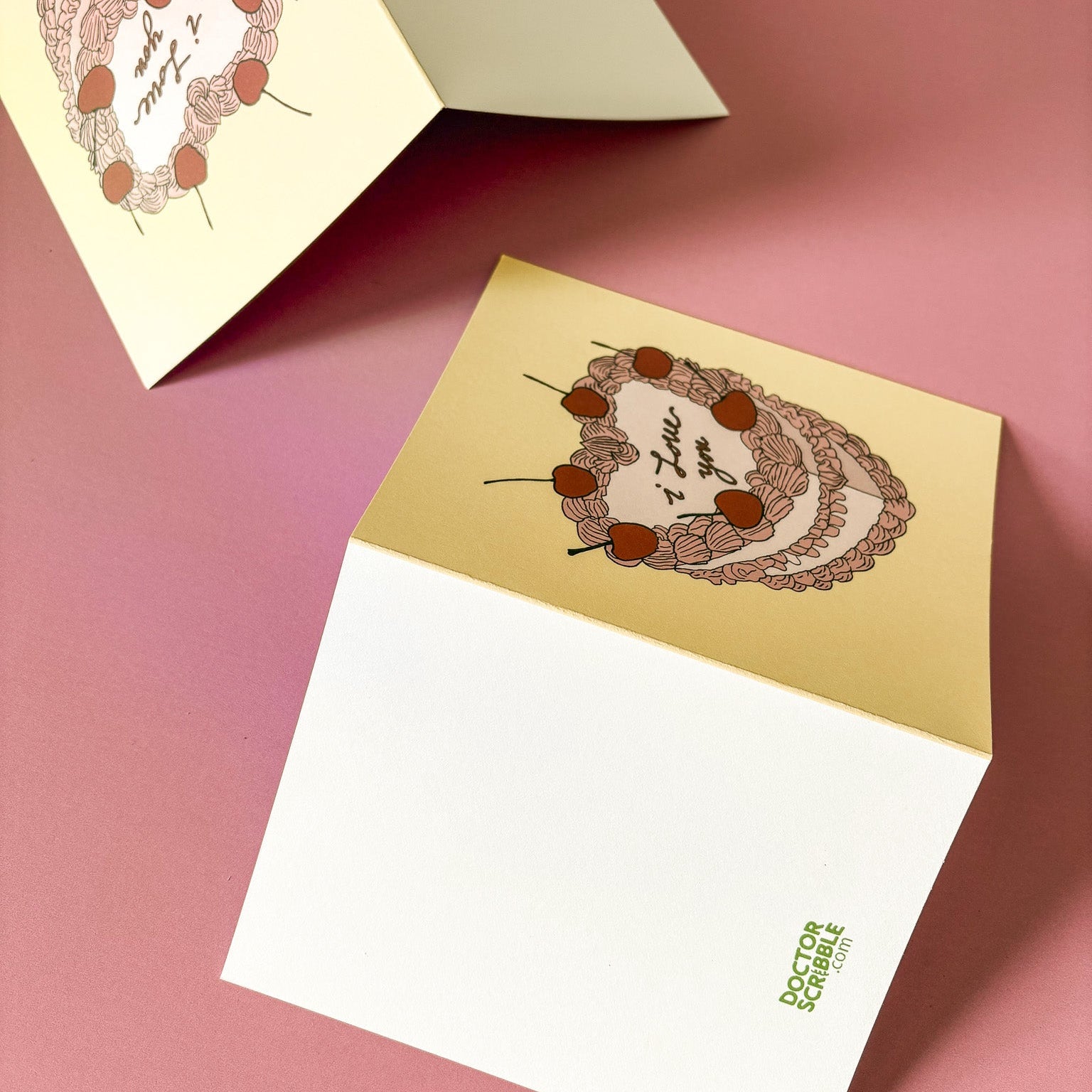 Two greeting cards with decorative designs on a pink background