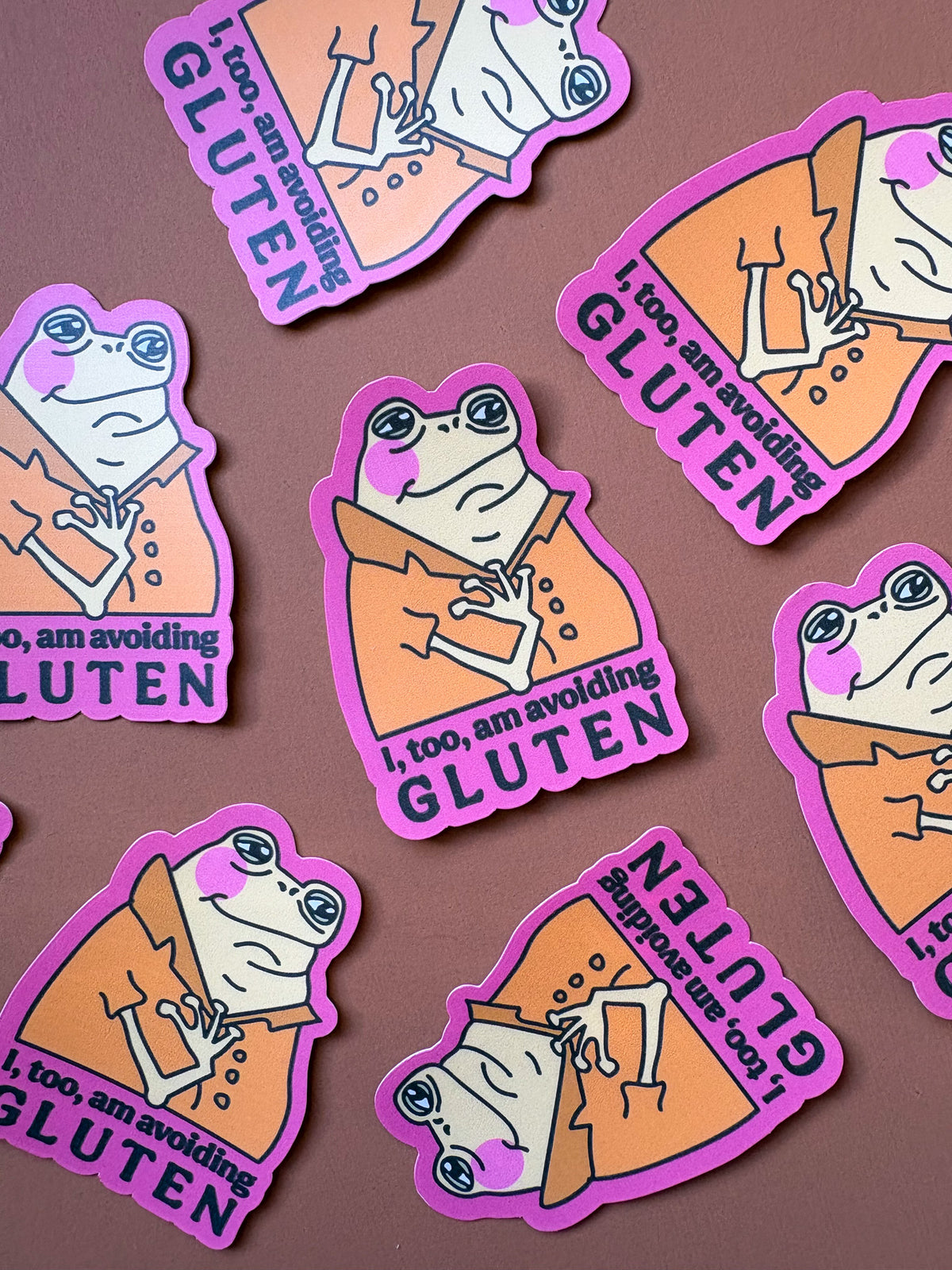 Front view of the pink-bordered frog sticker held in a hand