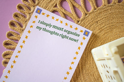 Notepad with text 'I simply must organize my thoughts right now!' on a decorative background