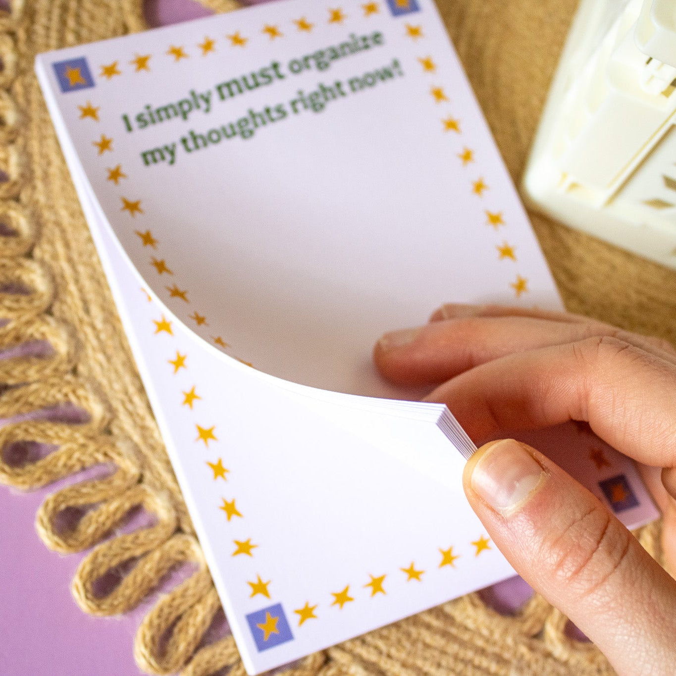 Hand holding a notepad with text and star designs on a textured surface