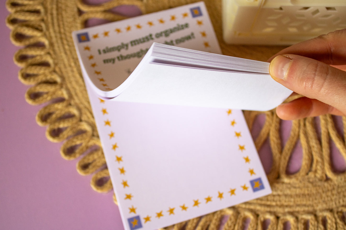Hand holding a notepad with gold stars on a textured surface.