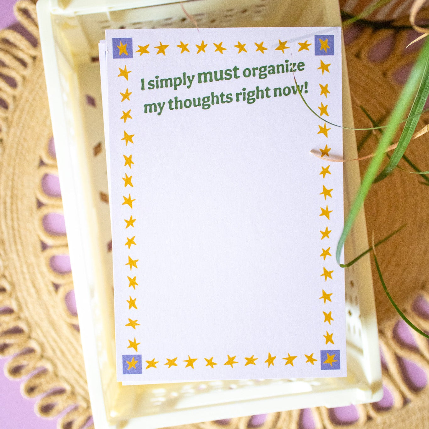 Notepad with a quote on a woven tray against a purple background