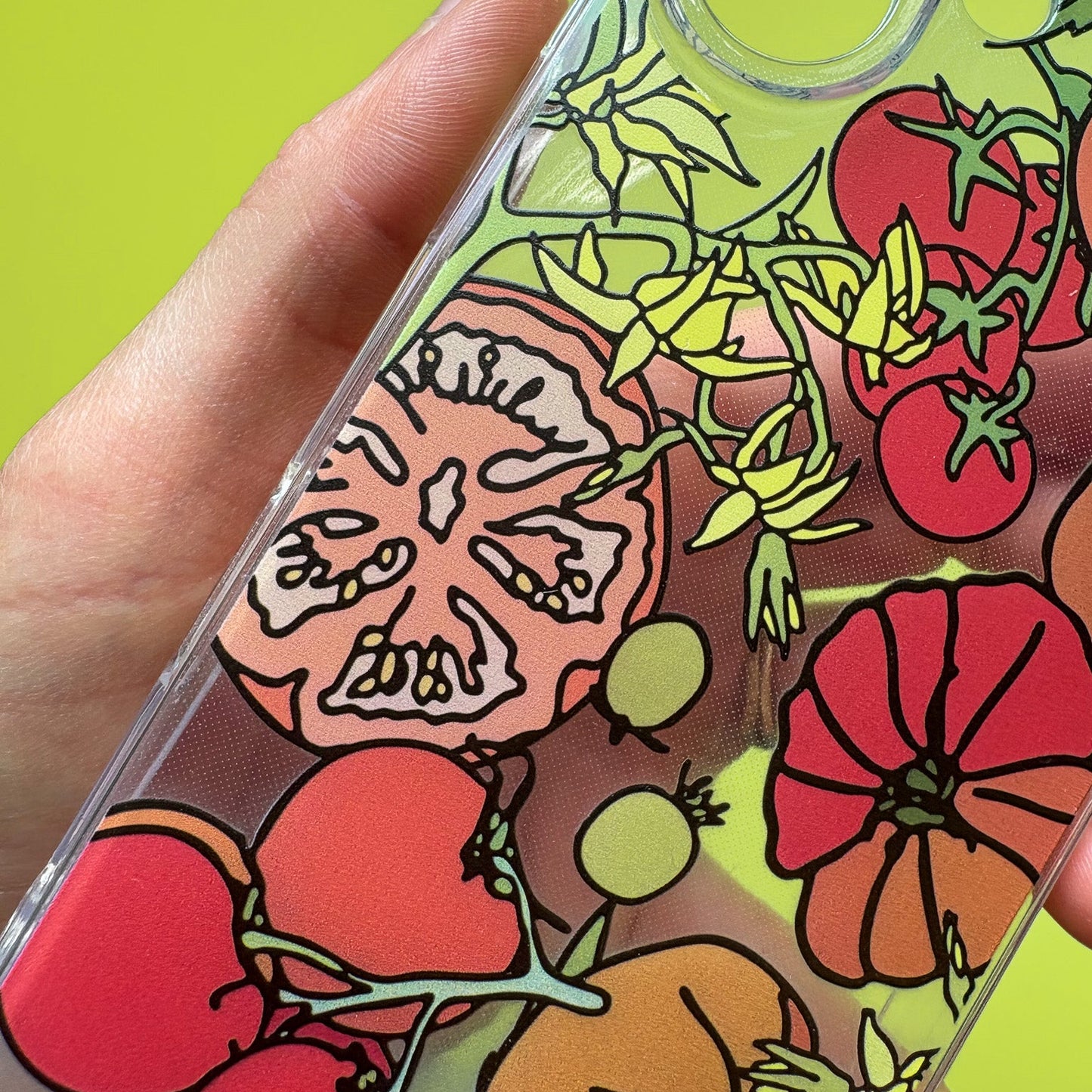 Phone case with colorful fruit illustrations held by a hand against a green background