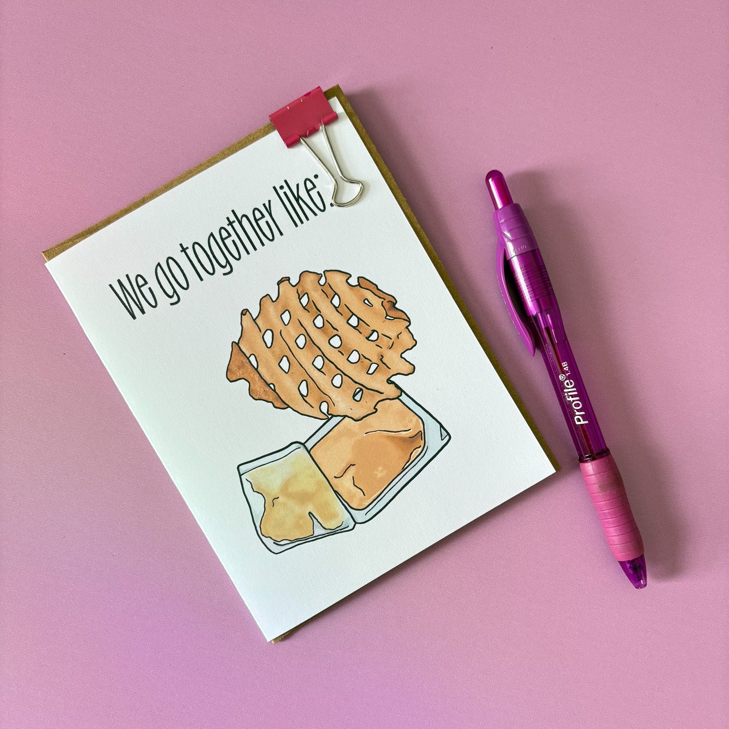 Card with a waffle fry illustration and a pink pen on a pink background